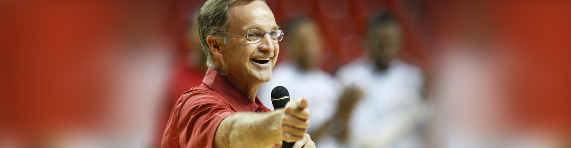 Lon Kruger with microphone in hand pointing