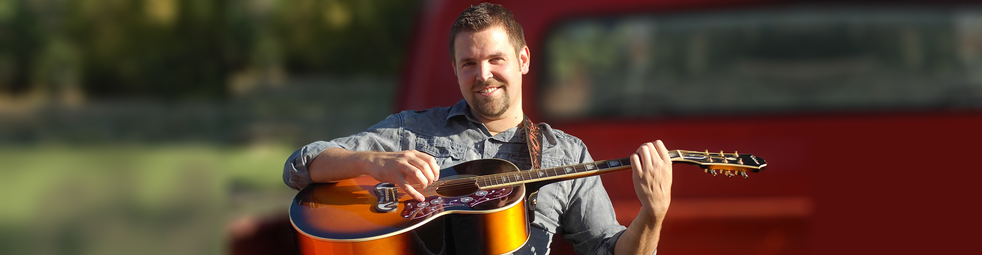 Nathan Osmond playing guitar with blurred truck in background