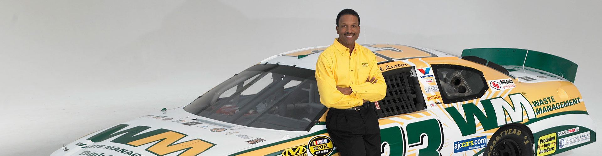 Bill Lester Leaning against racecar with arms crossed